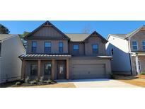 Two-story home with gray brick and a metal roof, featuring a front porch and attached garage at 4443 Eastbrook Pl, Snellville, GA 30039