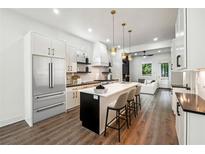 Modern, white kitchen featuring stainless steel appliances, a large island with seating, and hardwood floors at 1045 Mcdaniel St, Atlanta, GA 30310