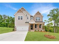 Charming two-story home with mixed siding, brick accents, and inviting front porch on a lush, green lawn at 7530 Homer Dr, Cumming, GA 30028