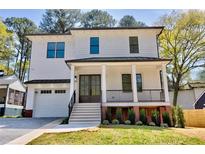 Charming two-story home with a white exterior, covered porch, landscaped yard, and attached garage at 2611 Charlesgate Ave, Decatur, GA 30030