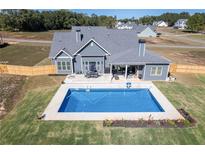 Aerial view of the home's private backyard pool with outdoor seating and well-manicured lawn at 255 Old Town Rd, Dacula, GA 30019