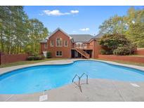 Inviting kidney-shaped pool in backyard with brick border at 512 Clearwater Dr, Mcdonough, GA 30252