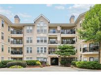 Condo building with multiple units, balconies, black railings, beige exterior, and manicured landscaping at 1850 Cotillion Dr # 3221, Dunwoody, GA 30338
