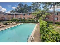 Relaxing community pool with lounge chairs surrounded by greenery and view of the apartment complex at 315 Hilderbrand Dr # C4, Sandy Springs, GA 30328