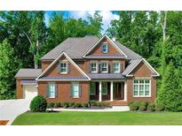 Beautiful brick home with a well-manicured lawn and lush green trees providing ample shade at 2423 Rosapenna Nw Ln, Kennesaw, GA 30152