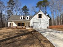 White farmhouse-style home with stone accents and a two-car garage at 90 Hammock Dr, Covington, GA 30016