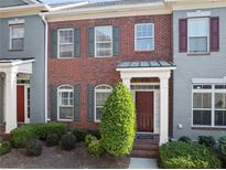 Charming brick townhome featuring a covered front porch, neat shrubbery and multi-pane windows at 10726 Austen Bnd, Alpharetta, GA 30022