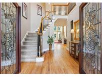 Grand foyer with hardwood floors, staircase, and decorative glass doors leading into the main living area at 1040 Avery Creek Dr, Woodstock, GA 30188