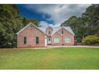 Charming brick home with a metal roof, a manicured lawn, and mature trees at 3598 Brock Rd, Duluth, GA 30096