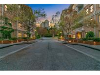 Condominiums line a quiet street, with warm lighting and views of the city skyline in the distance at 3621 Vinings Slope Se # 1537, Atlanta, GA 30339