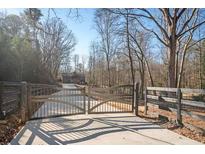 Long driveway with metal gates leading to a modern home nestled in woods at 600 Jones Rd, Roswell, GA 30075