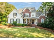 Charming two-story home features a welcoming front porch, brick accents, and lush landscaping at 6234 Creekstone Path, Cumming, GA 30041