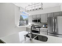 Modern kitchen features stainless steel appliances, gray cabinetry, a backsplash, and a quartz countertop at 2479 Peachtree Ne Rd # 105, Atlanta, GA 30305