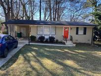 Charming single-story home with a manicured lawn, bright orange front door, and covered parking at 860 Verona Dr, Clarkston, GA 30021