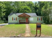 Charming green home with a cozy front porch, stone walkway and well-manicured lawn at 1204 Westridge Sw Rd, Atlanta, GA 30311