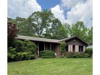 Charming brick home featuring a well-manicured lawn, mature trees, and a welcoming front porch at 1685 Dogwood Trl, Douglasville, GA 30134