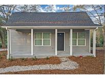 Charming gray cottage-style home with a welcoming front porch and gray roof, surrounded by trees and landscaping at 1815 River Ne St, Conyers, GA 30012