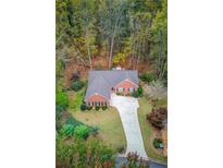 Brick house with driveway, surrounded by lush trees and landscaping at 868 Clarion Way, Lawrenceville, GA 30044