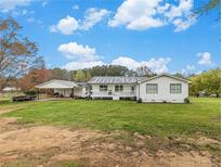 Charming home featuring a cozy front porch, well-maintained lawn, and a convenient two-car carport at 1871 Weems E Rd, Locust Grove, GA 30248