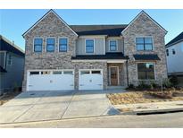 Two-story home with gray brick exterior, two-car garage, and landscaping at 4055 Hosch Retreat Dr, Buford, GA 30519