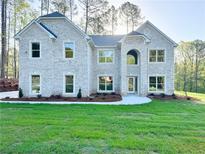 Elegant two-story home showcasing a striking white brick facade and meticulously manicured lawn at 5380 Deer Run Dr, Conyers, GA 30094