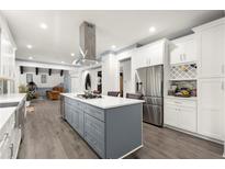 A spacious kitchen featuring stainless steel appliances, gray cabinets, and an island with a cooktop at 2680 Spalding Dr, Sandy Springs, GA 30350