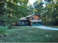 Ranch style home with wood siding, two-car garage, and a spacious yard at 100 Lakeside Dr, Covington, GA 30016