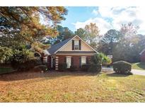 Charming brick home with manicured landscaping and a basketball hoop in the driveway at 210 Huiet Dr, Mcdonough, GA 30252