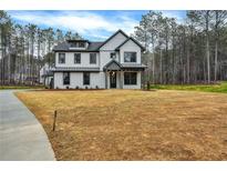 Beautiful two-story home with black trim, dormer windows, a manicured lawn, and mature trees at 3745 Pilgrim Mill Rd, Cumming, GA 30041