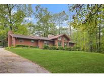 Charming single-story home with large windows, mature trees, and a lush green lawn at 10 Gentry Dr, Mcdonough, GA 30252