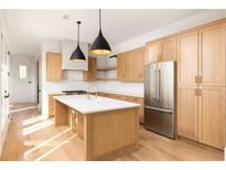 Bright kitchen with light wood cabinets, stainless steel appliances, pendant lights, and a large center island at 10931 Serenbe Ln, Chattahoochee Hills, GA 30268