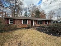 Charming brick home featuring red shutters, complemented by a naturally landscaped front yard at 1981 Bramblewood Ne Dr, Brookhaven, GA 30329