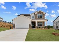 Charming two-story home featuring a stone facade, a two-car garage, and a beautifully landscaped front yard at 7675 Homer Dr, Cumming, GA 30028