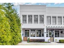 Modern townhome with white brick facade, trimmed hedges and lush green tree at 212 Sessions St, Woodstock, GA 30188
