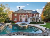 Stunning brick home featuring a large pool and integrated hot tub, perfect for outdoor relaxation at 2195 Lake Shore Lndg, Alpharetta, GA 30005