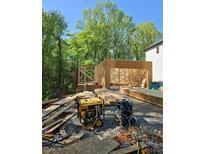 New construction of a home with lumber and equipment on the grounds surrounded by mature trees at 1664 Crestridge Se Dr, Marietta, GA 30067