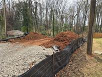 View of a construction site with gravel, soil, and silt fencing surrounded by trees at 1664 Crestridge Se Dr, Marietta, GA 30067