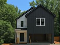 Charming two-story home with a black and white color scheme, attached garage, and lush green trees in the background at 1664 Crestridge Se Dr, Marietta, GA 30067