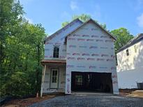Two-story home's exterior is under construction with an attached two-car garage and wooded backdrop at 1664 Crestridge Se Dr, Marietta, GA 30067