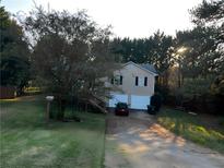 Charming two-story home with a two-car garage and inviting driveway nestled among lush green trees at 49 Sweetwater Ct, Powder Springs, GA 30127