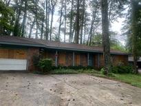 Brick ranch house with boarded windows, needs renovation. Located on a wooded lot at 2328 Columbia Dr, Decatur, GA 30032