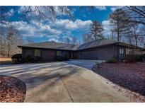 Ranch style home with dark exterior, attached garage, and long driveway at 110 Cove Ln, Social Circle, GA 30025