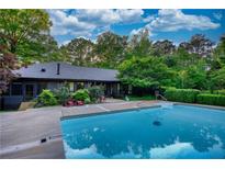 Inviting pool with a concrete surround and lush greenery, perfect for relaxing and entertaining guests at 110 Cove Ln, Social Circle, GA 30025