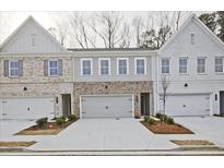 Charming townhome featuring a two-car garage and diverse brick and siding accents at 697 Sunstone Ln, Lawrenceville, GA 30043