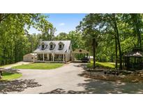 Charming home featuring a metal roof, covered porch, carport and a beautifully landscaped yard with mature trees at 291 Miquel Jorge Ln, Canton, GA 30115