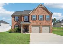 Beautiful two-story brick home featuring an attached two-car garage and a well-manicured lawn at 1363 Midnight Ride Ct, Hampton, GA 30228