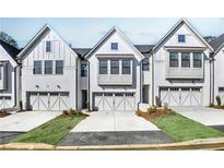 Three-unit townhome building with white brick and gray accents, two-car garages, and landscaping at 132 Briargate Dr, Johns Creek, GA 30097