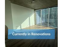 Bright living room featuring wood flooring, neutral walls, and expansive windows with city views at 855 Peachtree St # 2205, Atlanta, GA 30308