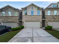 Charming townhome featuring a brick facade, a two-car garage, and a well-maintained lawn at 3279 Wild Basil Ln, Buford, GA 30519