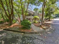 Inviting two-story condo featuring a charming balcony, lush greenery, and a tree-lined walkway at 504 Vicksburg Pl, Atlanta, GA 30350